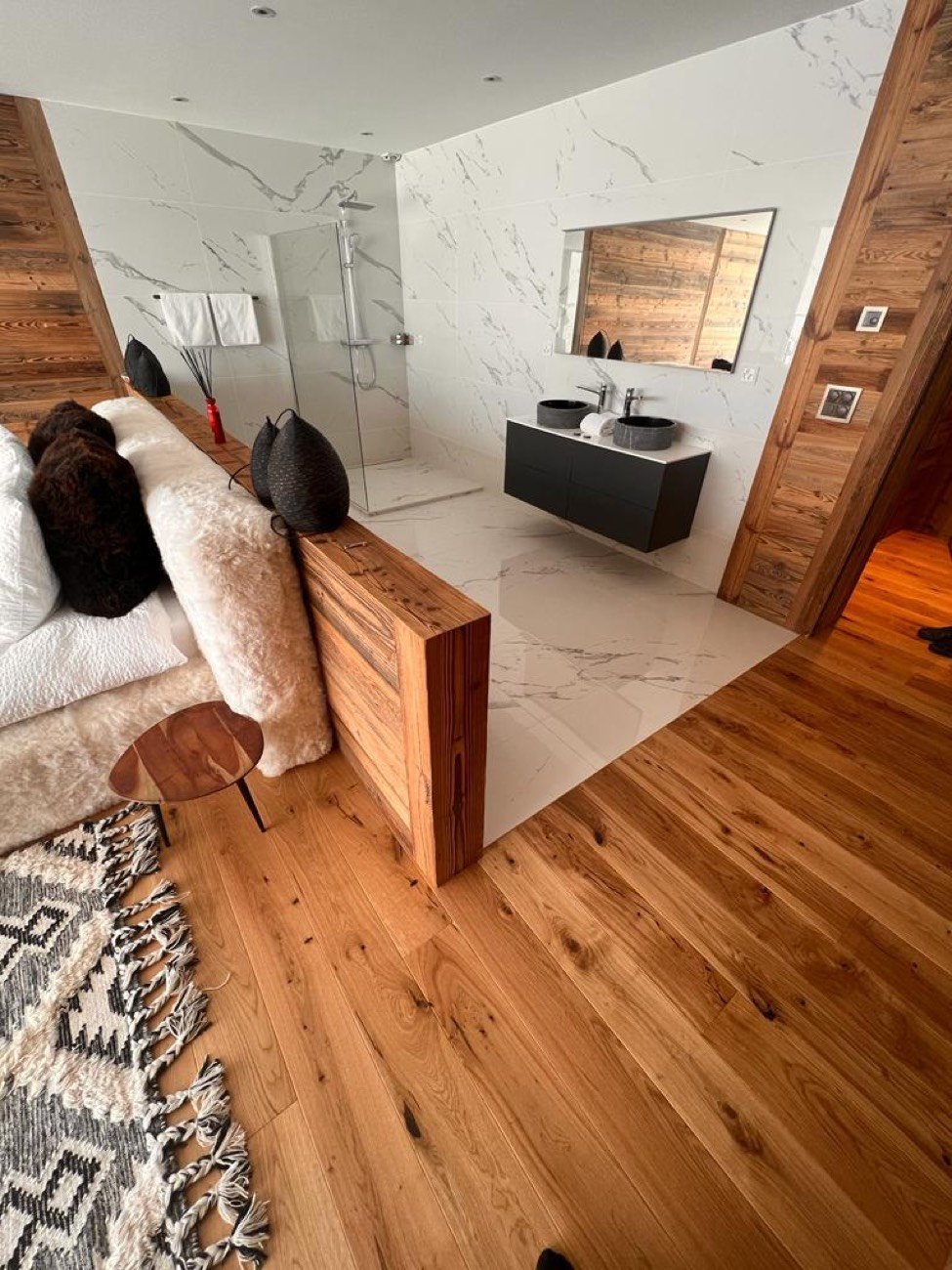 Suite parentale en chalet avec salle de bains ouverte, carrelage effet marbre, vieux bois et vasque à poser