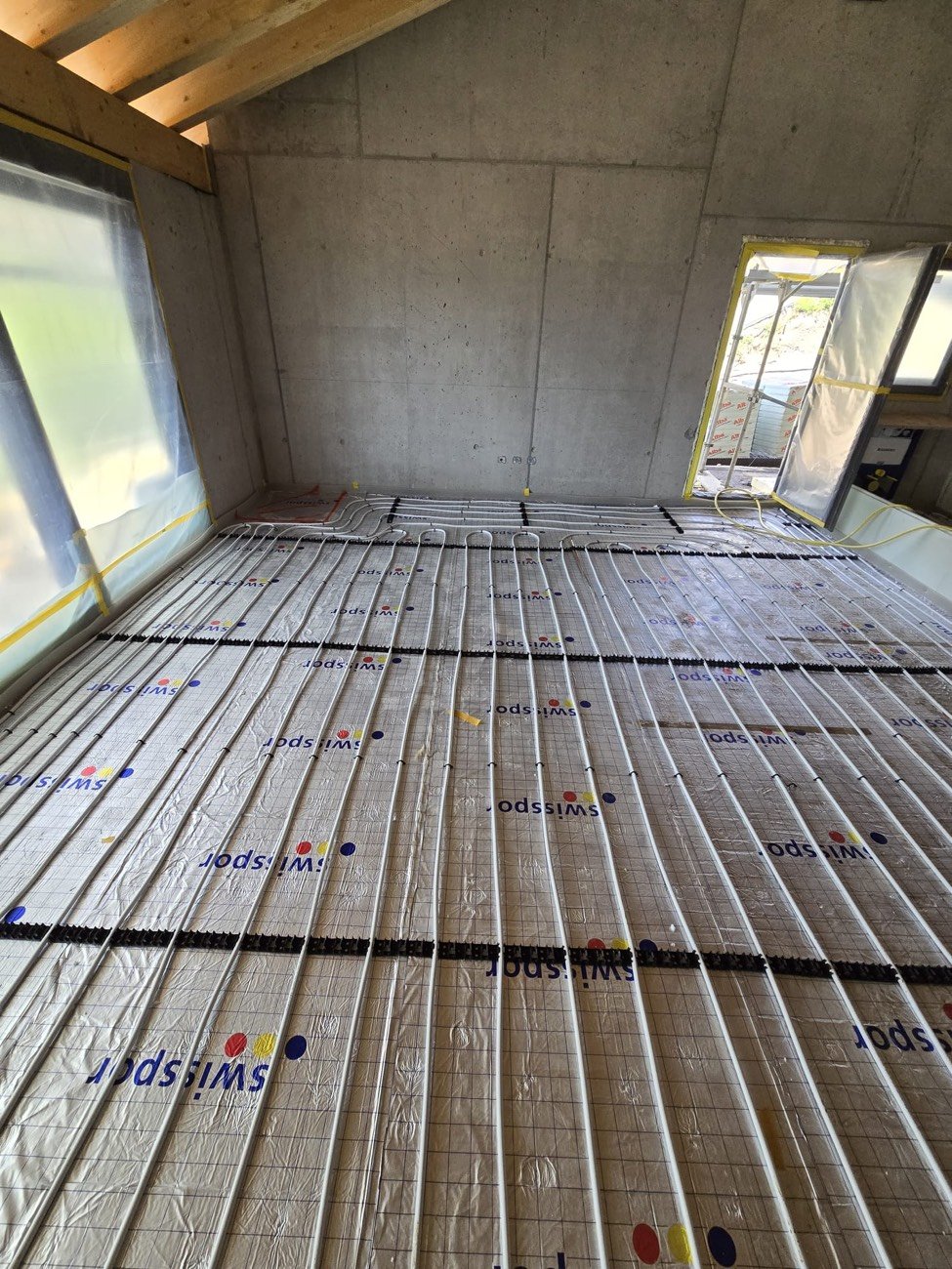 Pose de tubes de chauffage au sol sur panneaux isolants dans une construction neuve