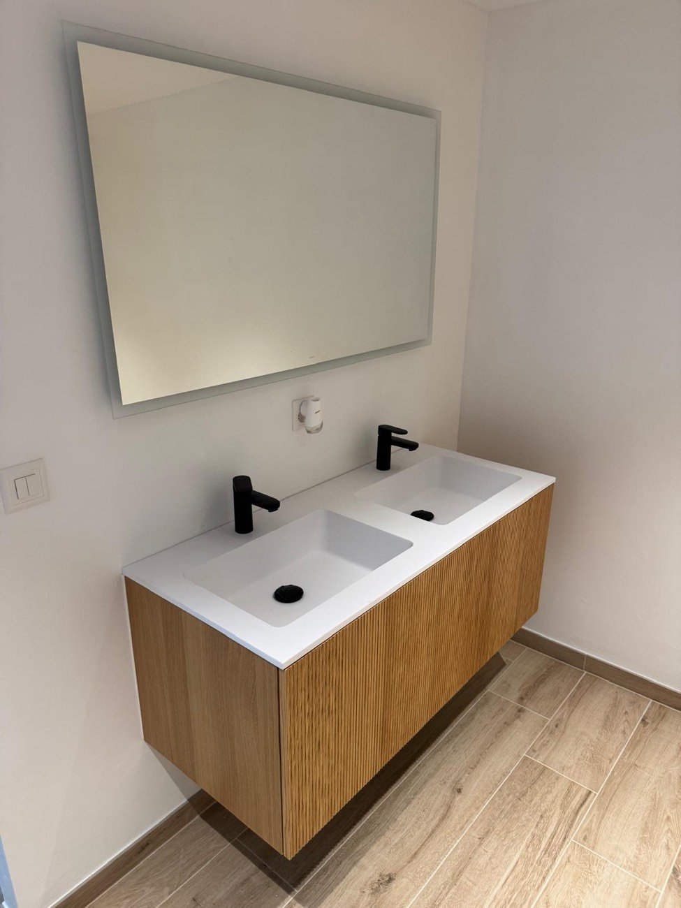 Meuble double vasque en bois avec plan blanc, robinetterie noire et grand miroir
