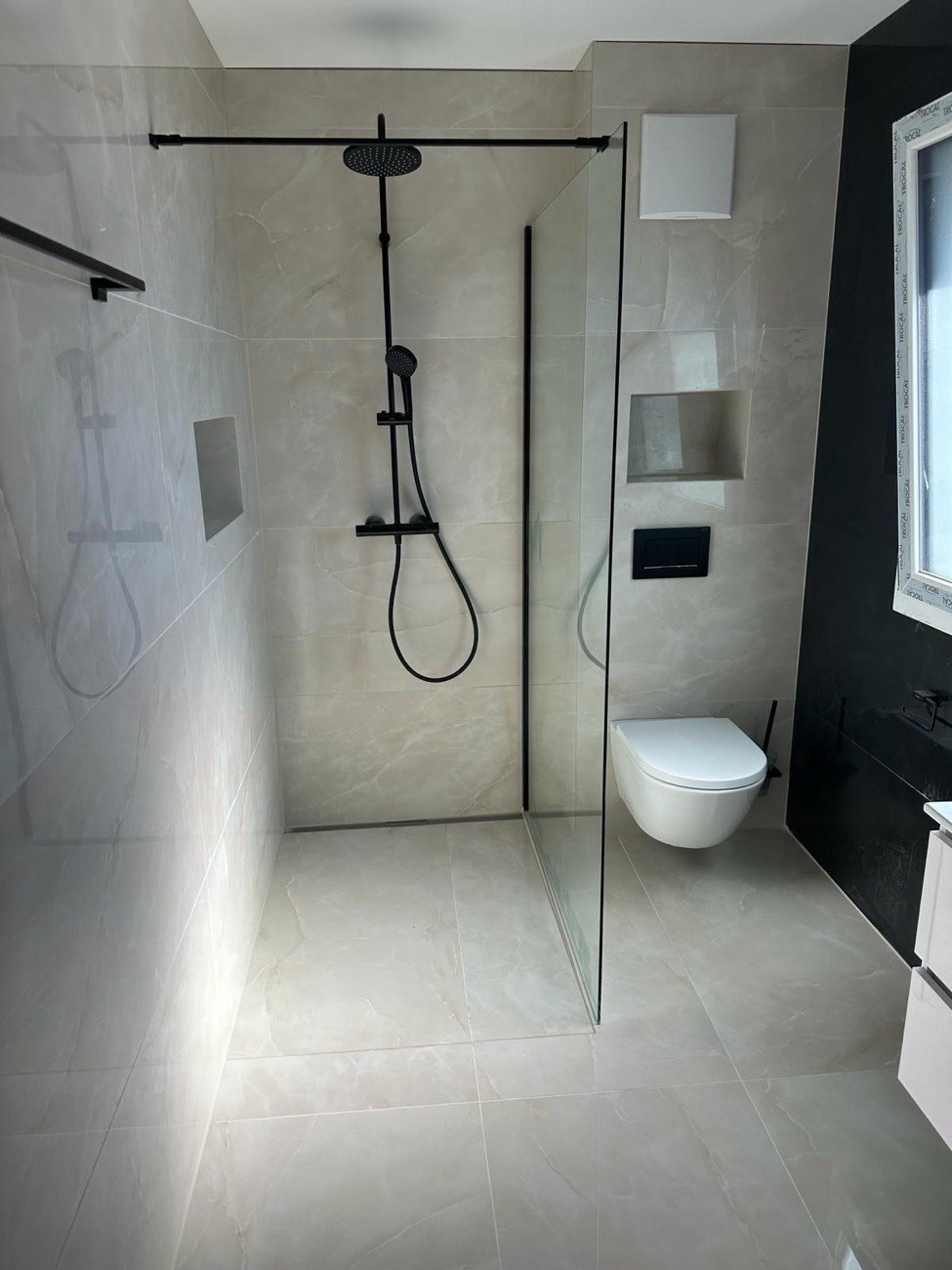 Douche à l'italienne avec paroi vitrée, colonne de douche noir mat et WC suspendu