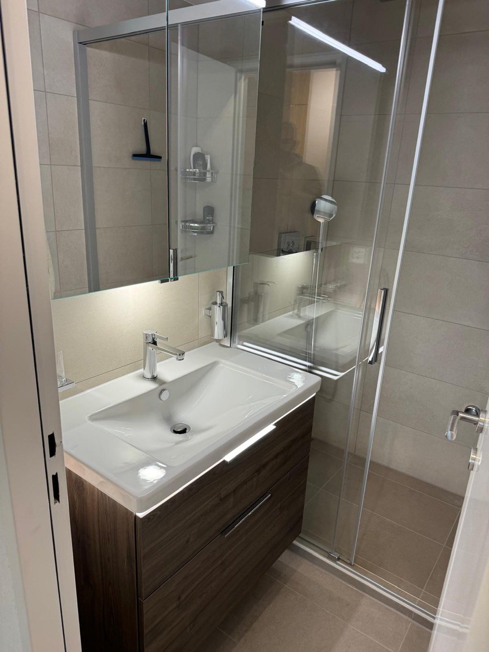 Après la rénovation : grande douche vitrée, meuble vasque en bois et carrelage clair
